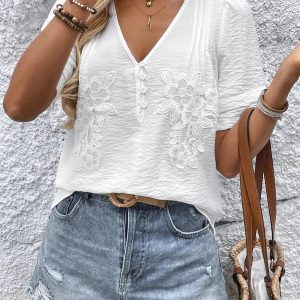 Vit crêppad blus med blommiga applikationer